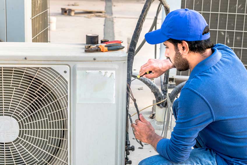 ac specialist fixing the heavy air conditioner